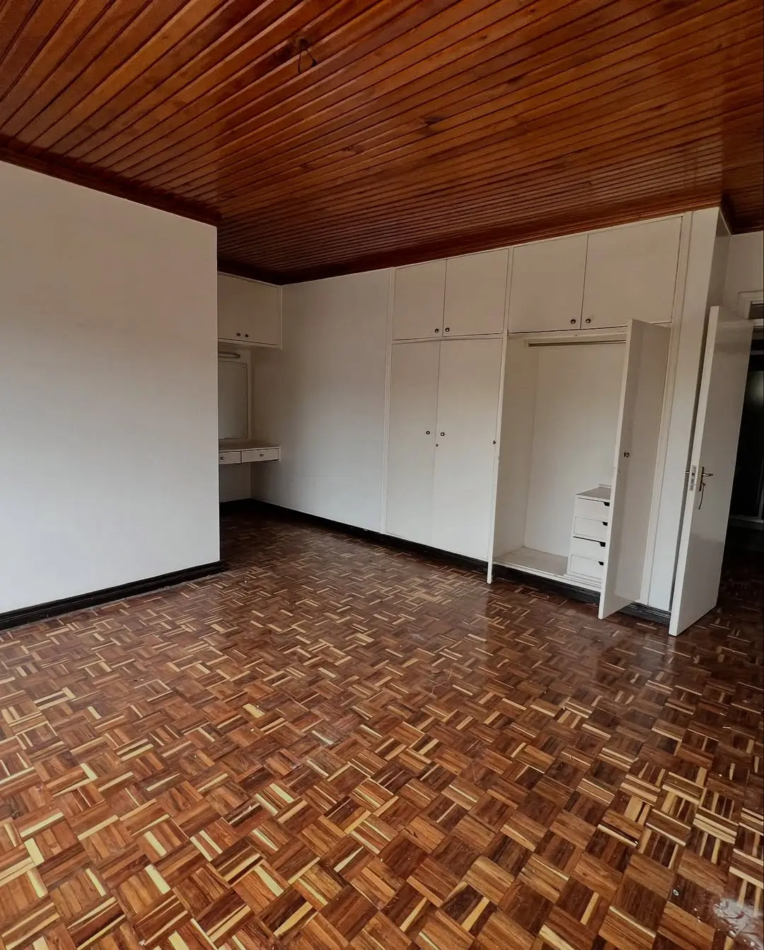 Spacious bedroom with wooden ceiling and built-in wardrobes