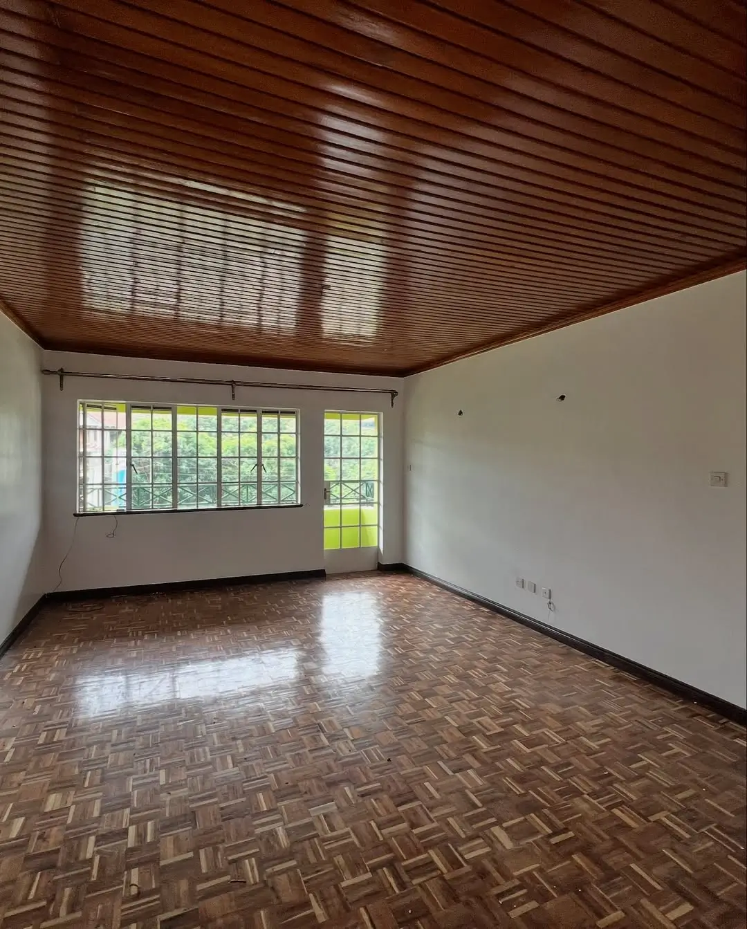 Spacious living room with wooden ceiling and herringbone flooring