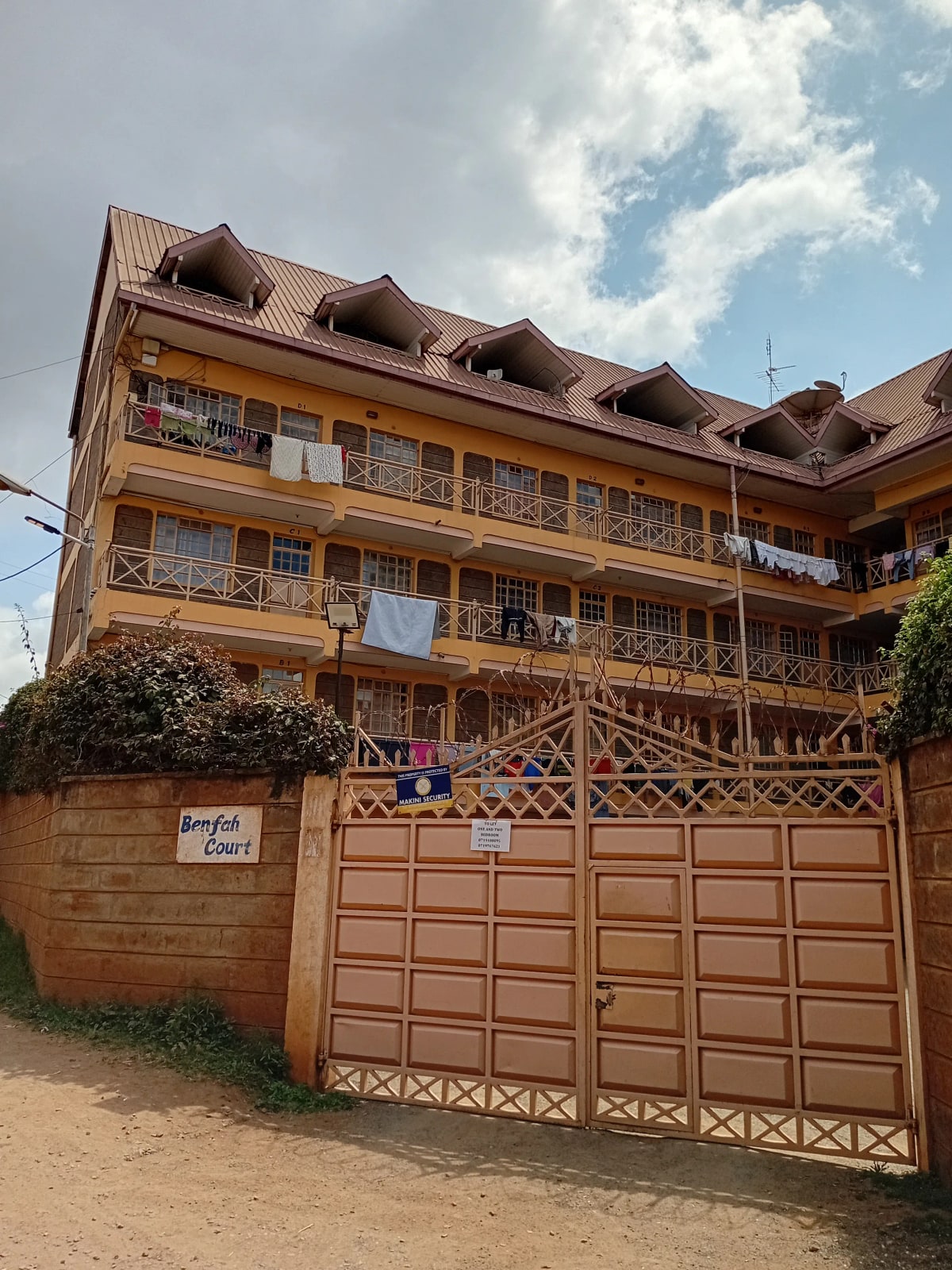 Multi-story residential building with wooden gate and compound entrance