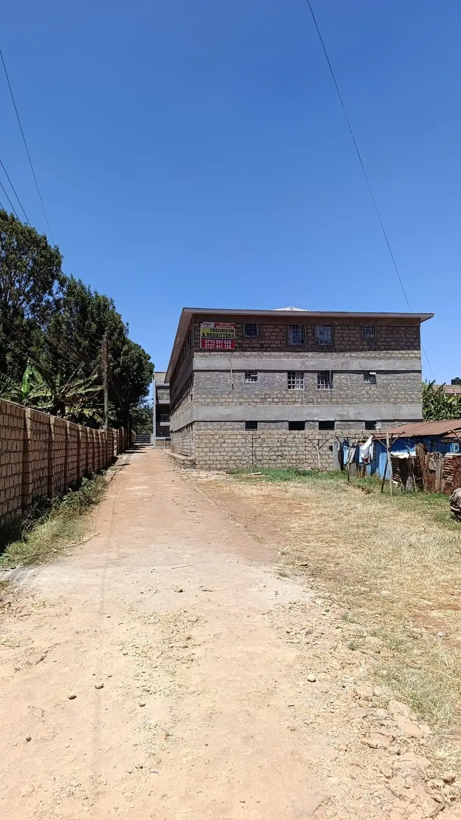 Multi-story residential building with dirt compound entrance