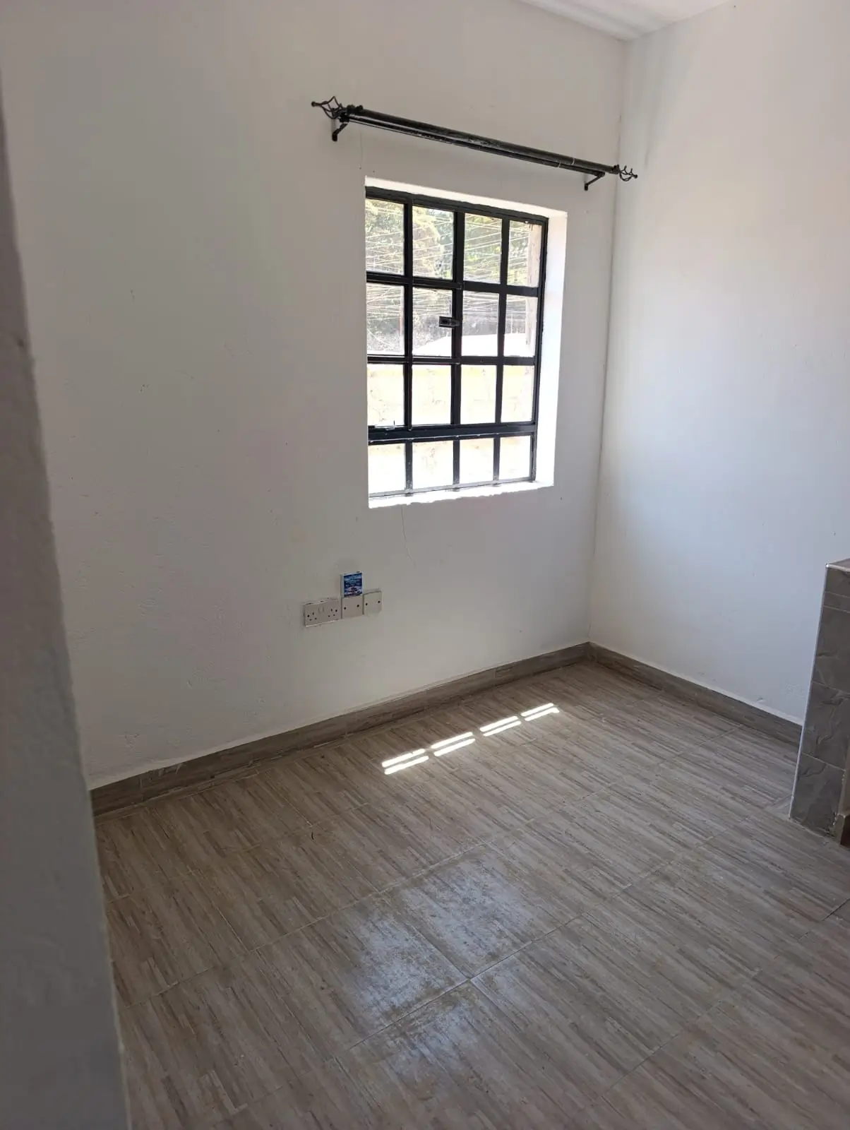 Unfurnished bedroom with wooden flooring and barred window