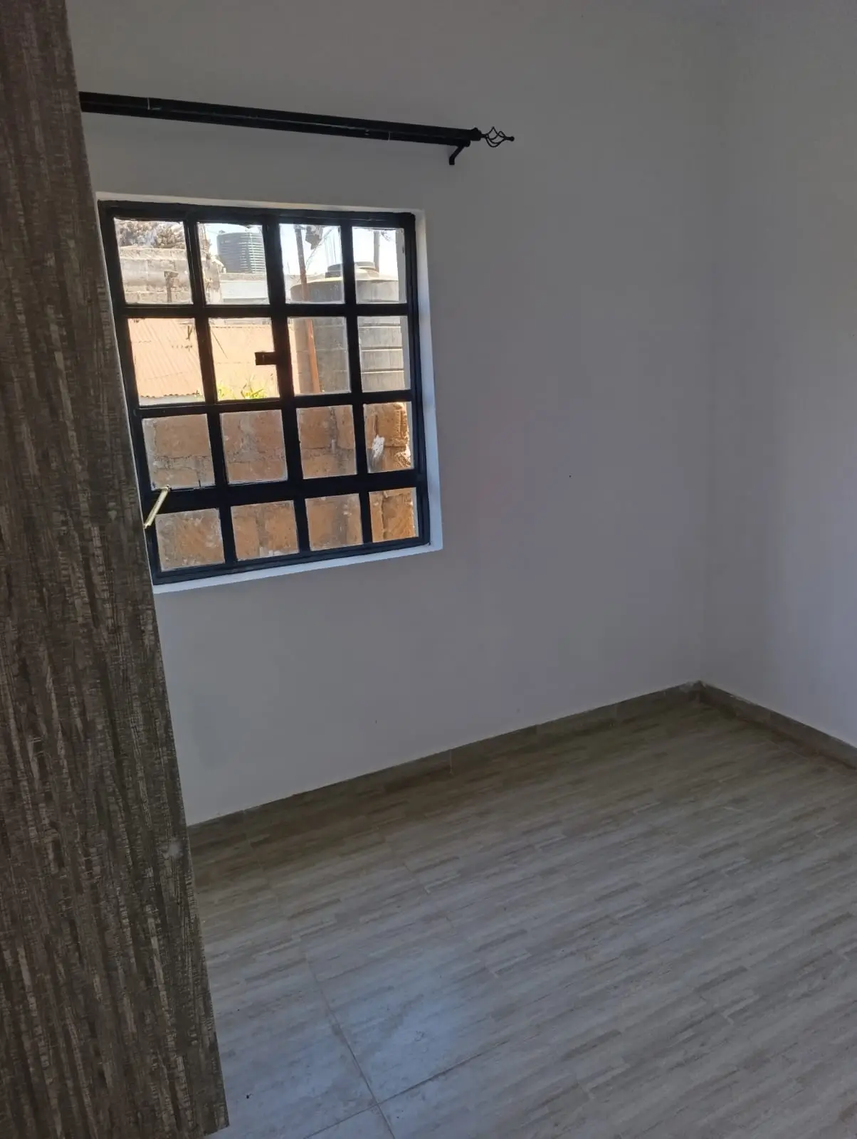 Unfurnished bedroom with wooden flooring and grid window