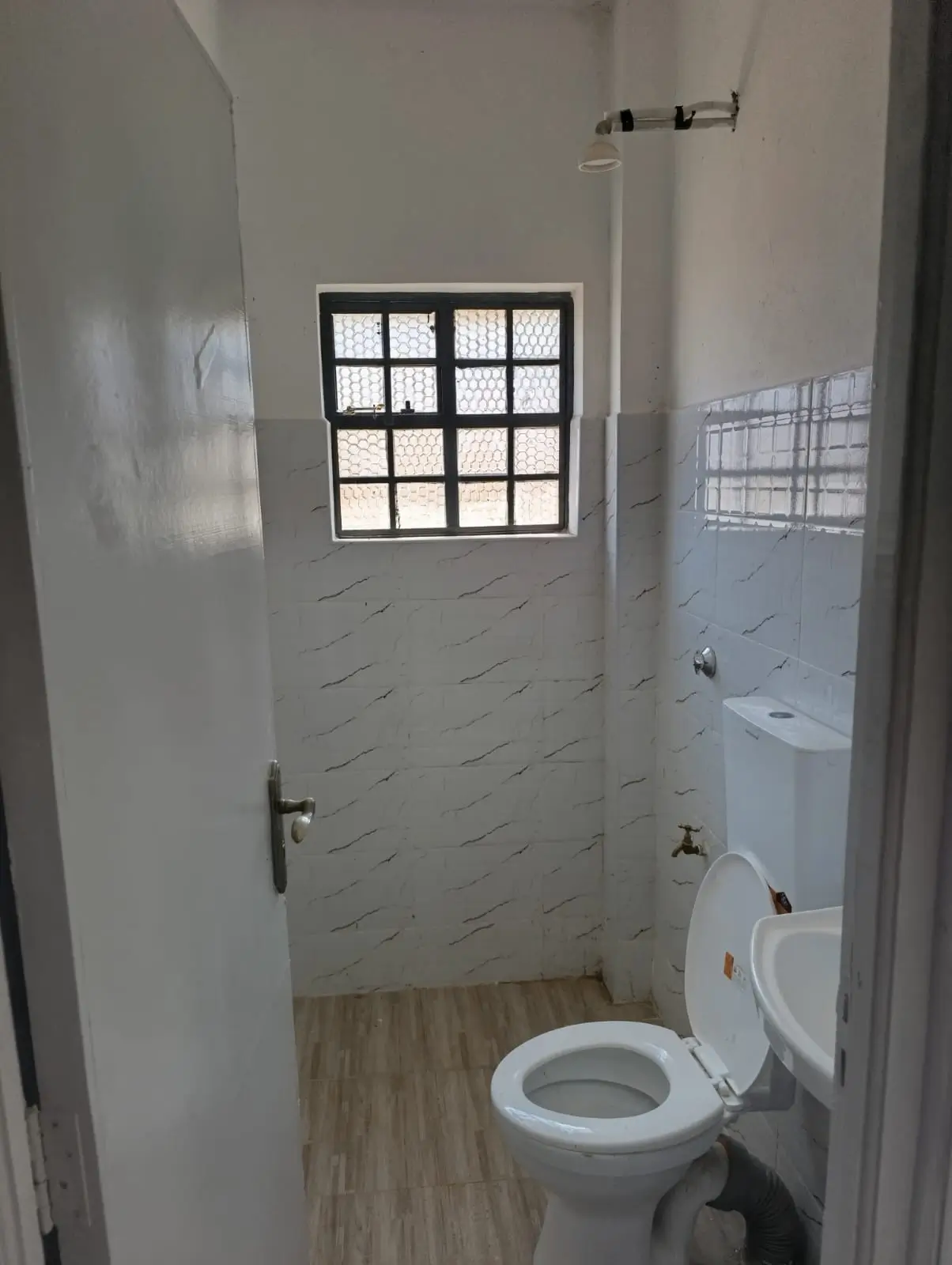 Compact bathroom with toilet, sink, and small window