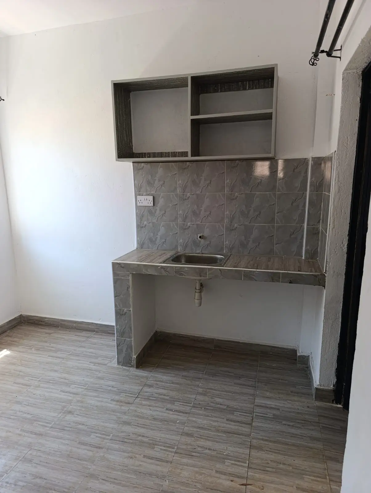 Compact kitchenette with gray tile backsplash and shelving