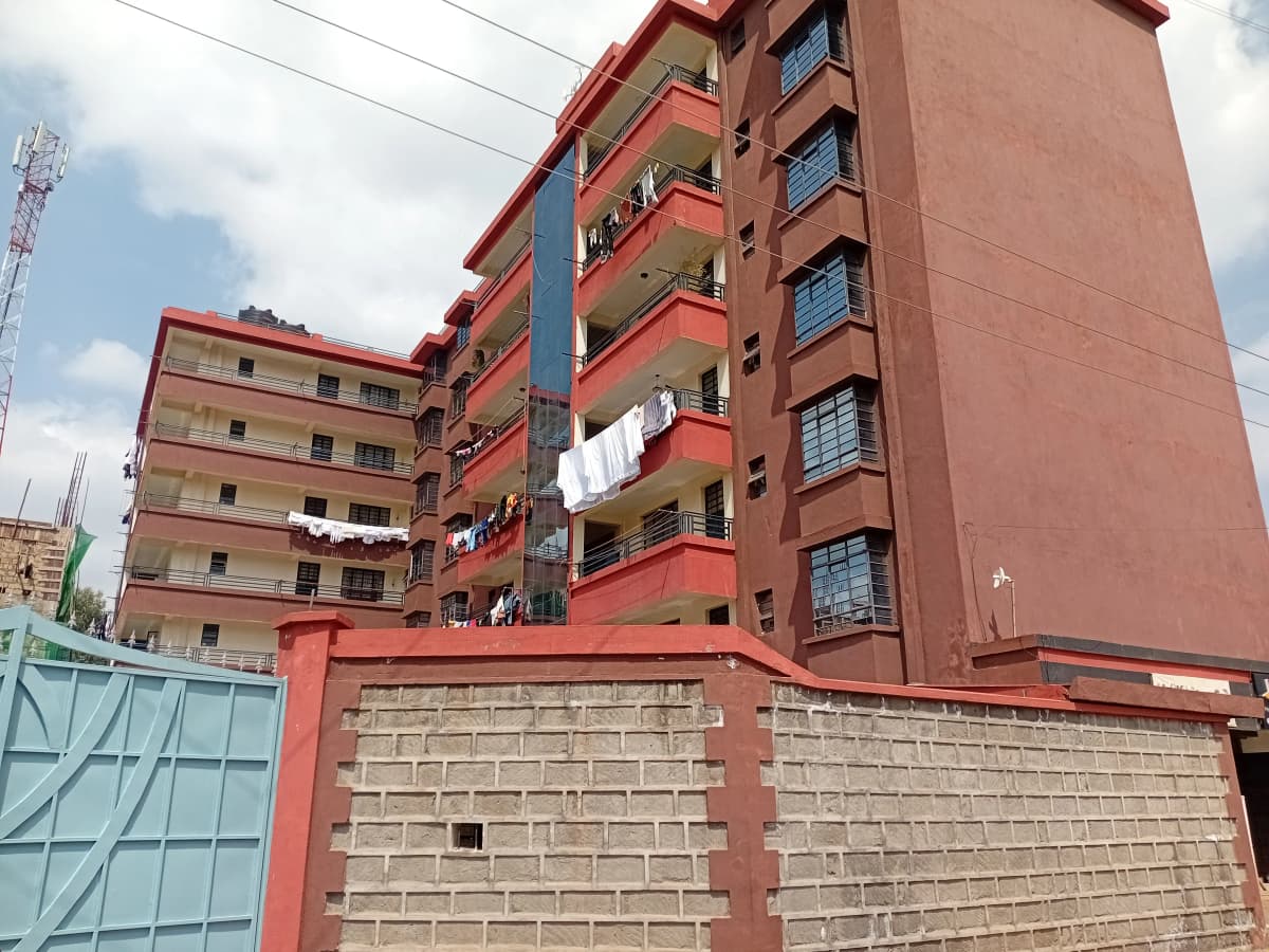 Red brick multi-story apartment building with balconies and gate
