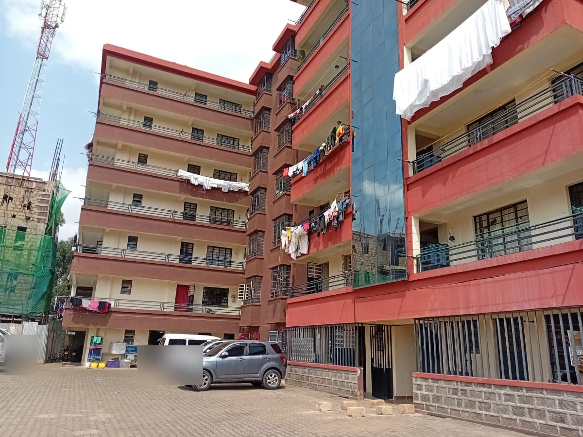 Red multi-story residential building with ground-level parking bay