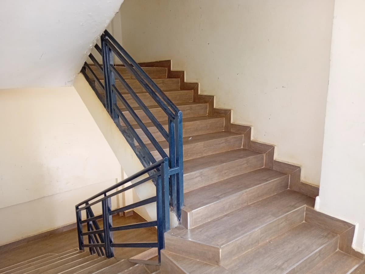 Interior staircase with blue metal railing and wooden steps