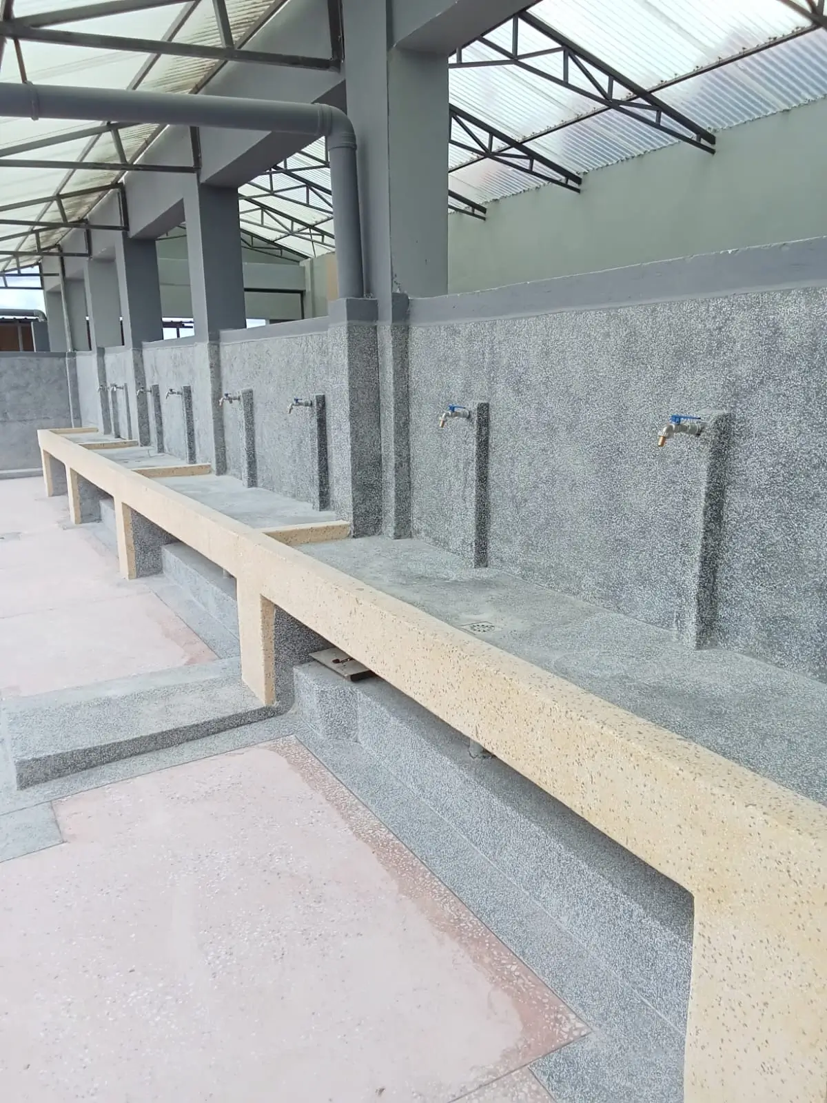 Communal laundry area with concrete wash basins and taps