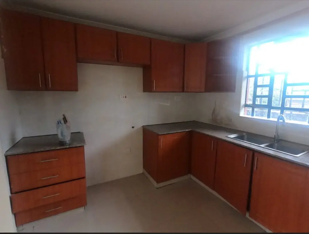 L-shaped kitchen with reddish-brown cabinets and dark countertops
