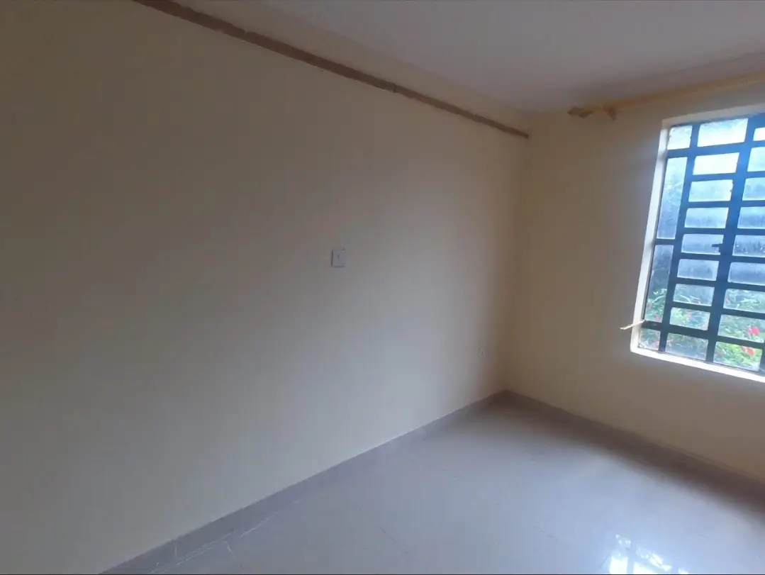 Bright empty bedroom with large window and polished floor
