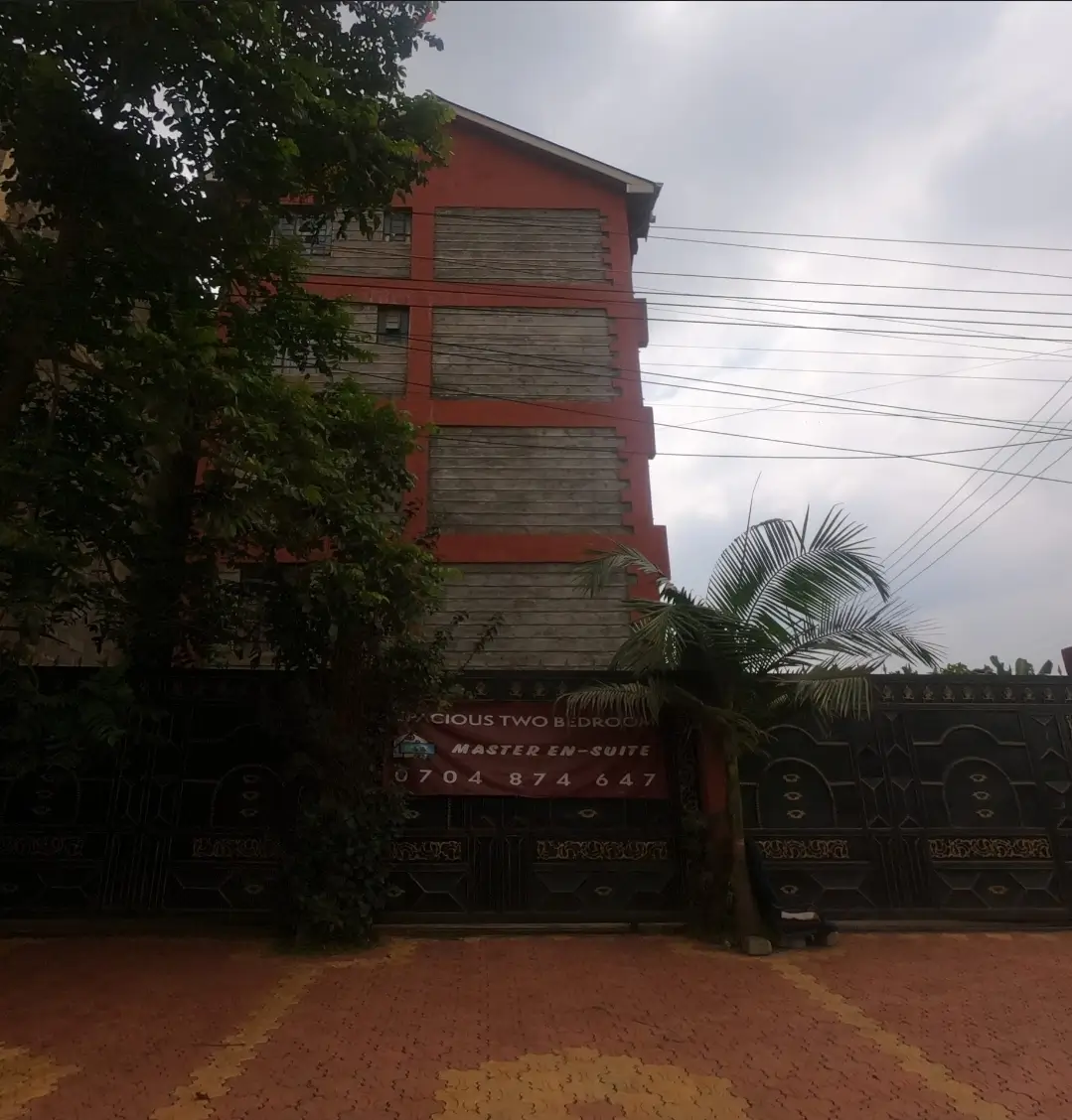 Red and grey multi-story building facade with compound gate