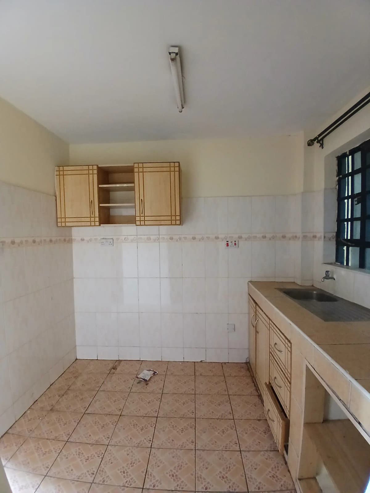 Basic kitchen with wooden cabinets and terracotta tile flooring