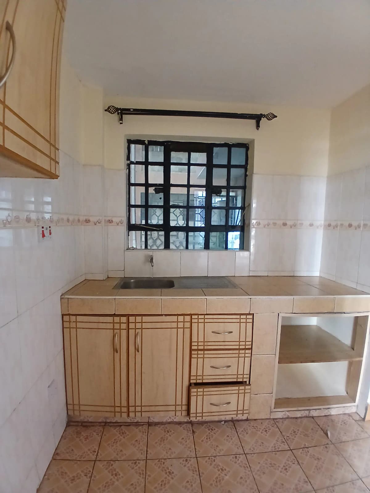 Compact kitchen with wooden cabinetry and tiled countertop