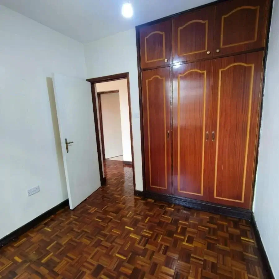 Spacious bedroom with wooden wardrobe and parquet flooring