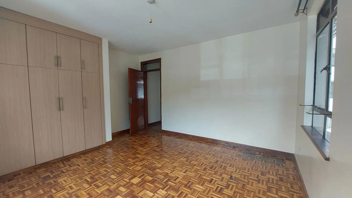 Spacious bedroom with built-in wardrobes and herringbone flooring