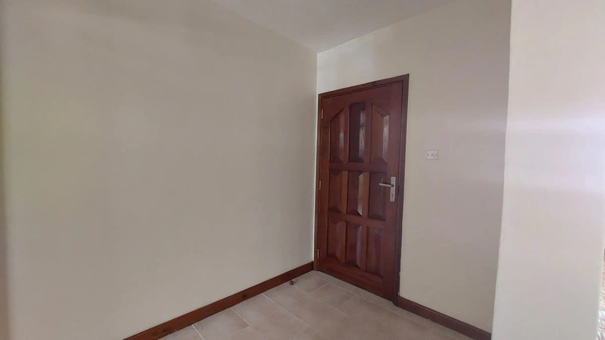 Empty bedroom with wooden door and plain walls