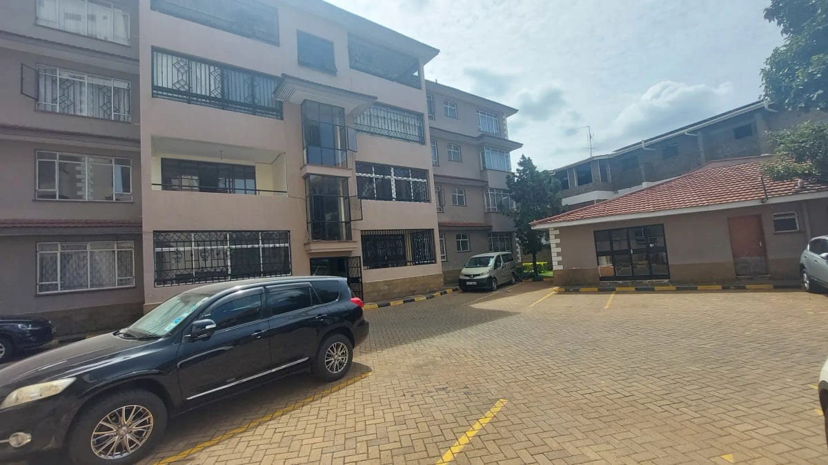 Paved compound parking area with multi-story residential building