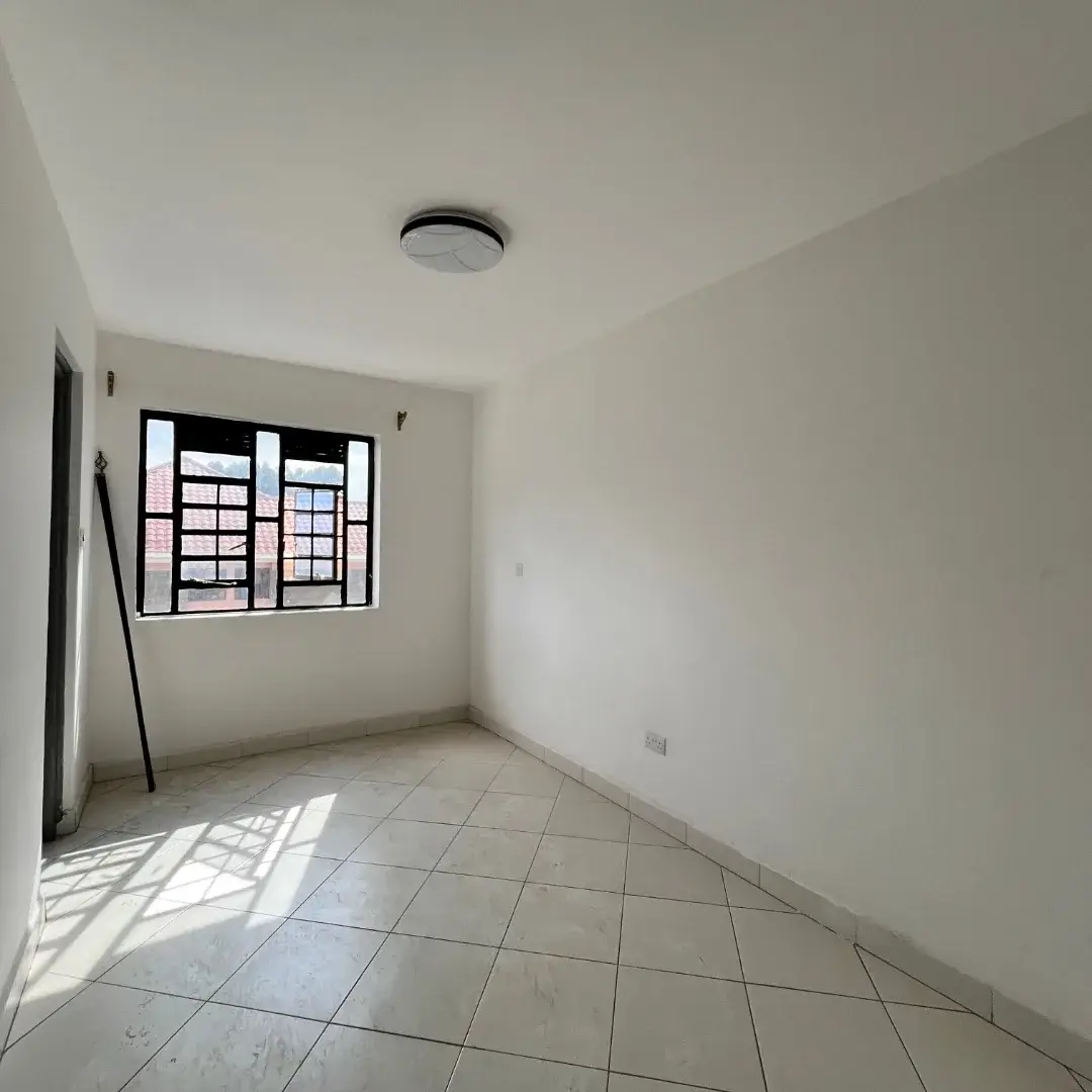 Bright empty bedroom with barred window and tile flooring