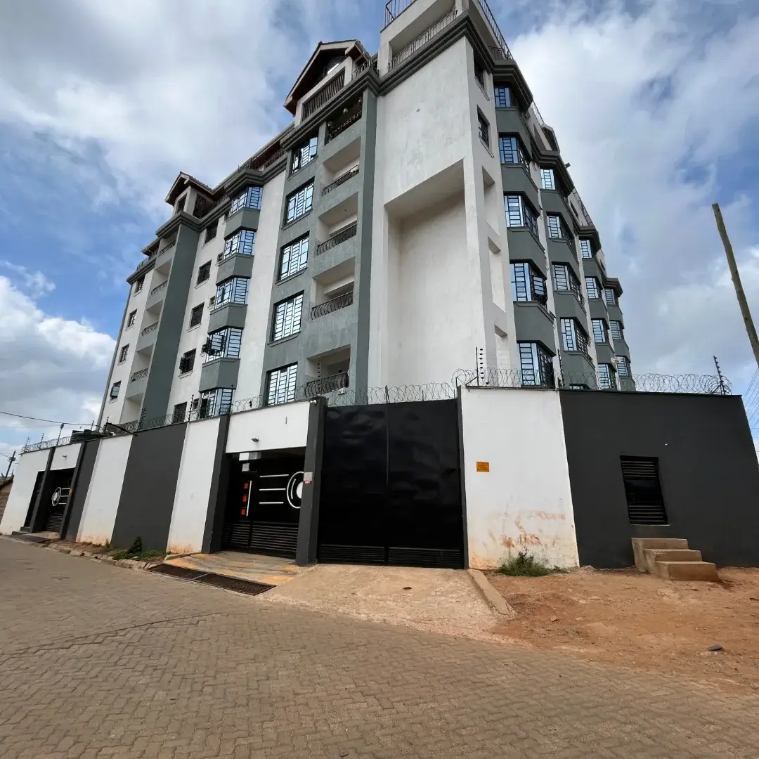 Modern multi-story residential building with gated parking entrance