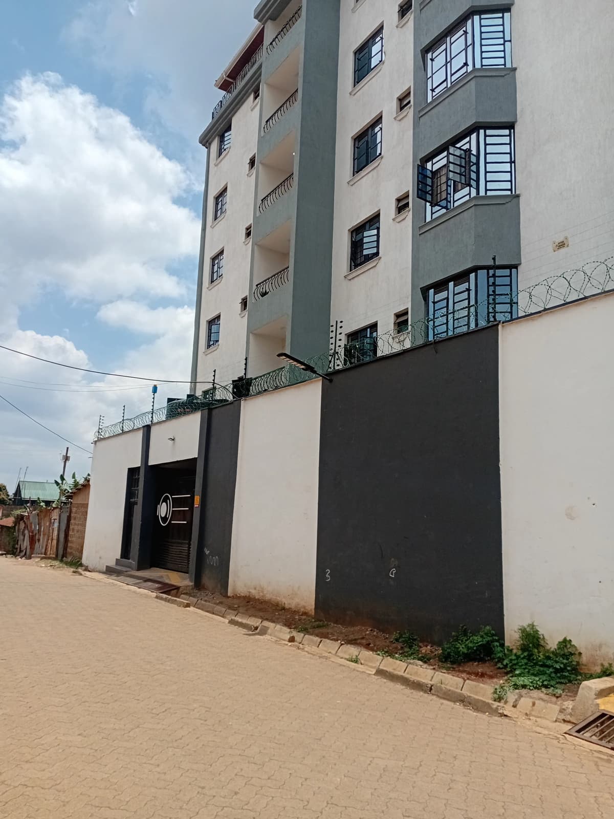 Multi-story apartment building with gated entrance and compound