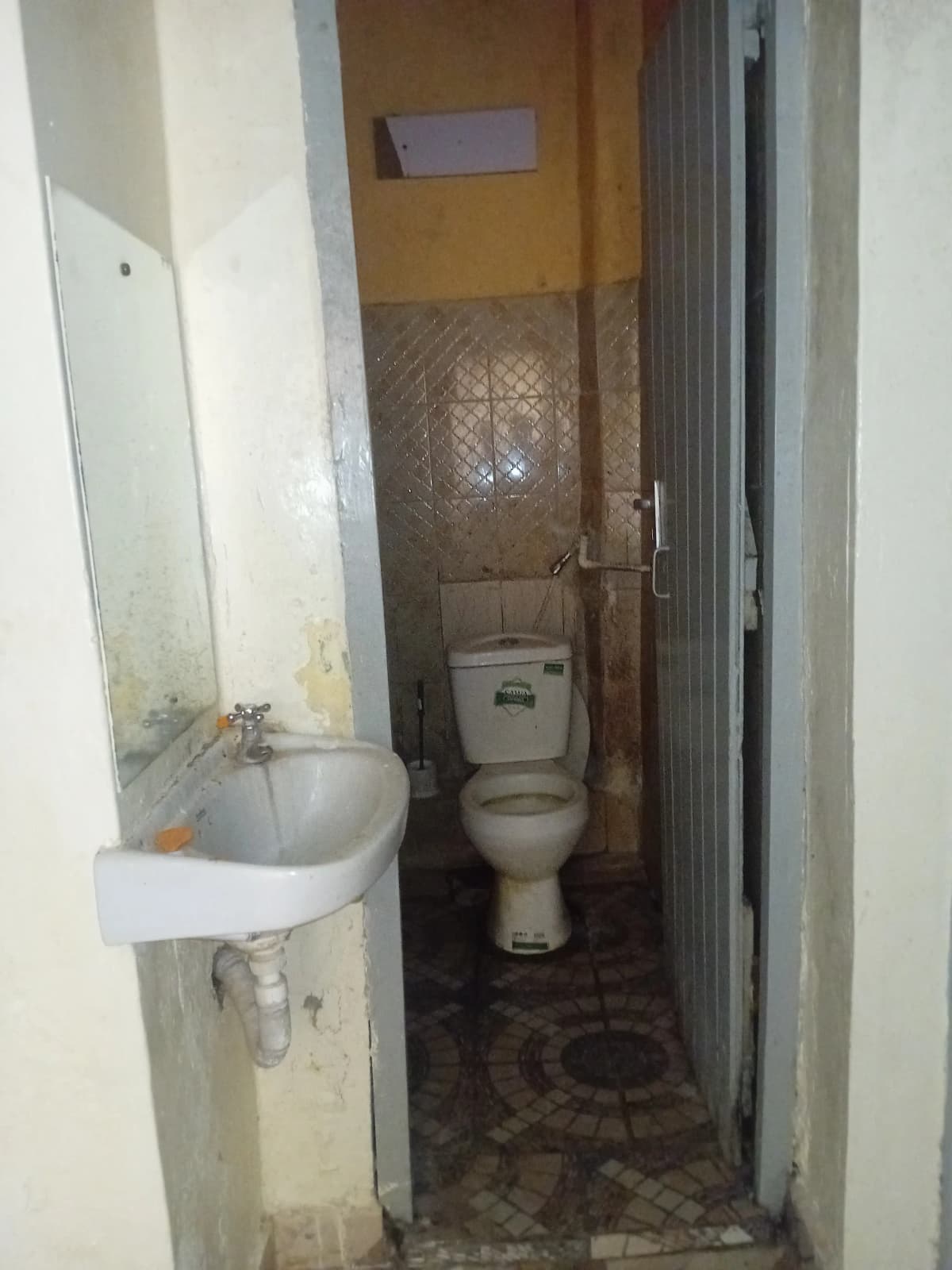 Compact bathroom with pedestal sink and toilet, tiled walls