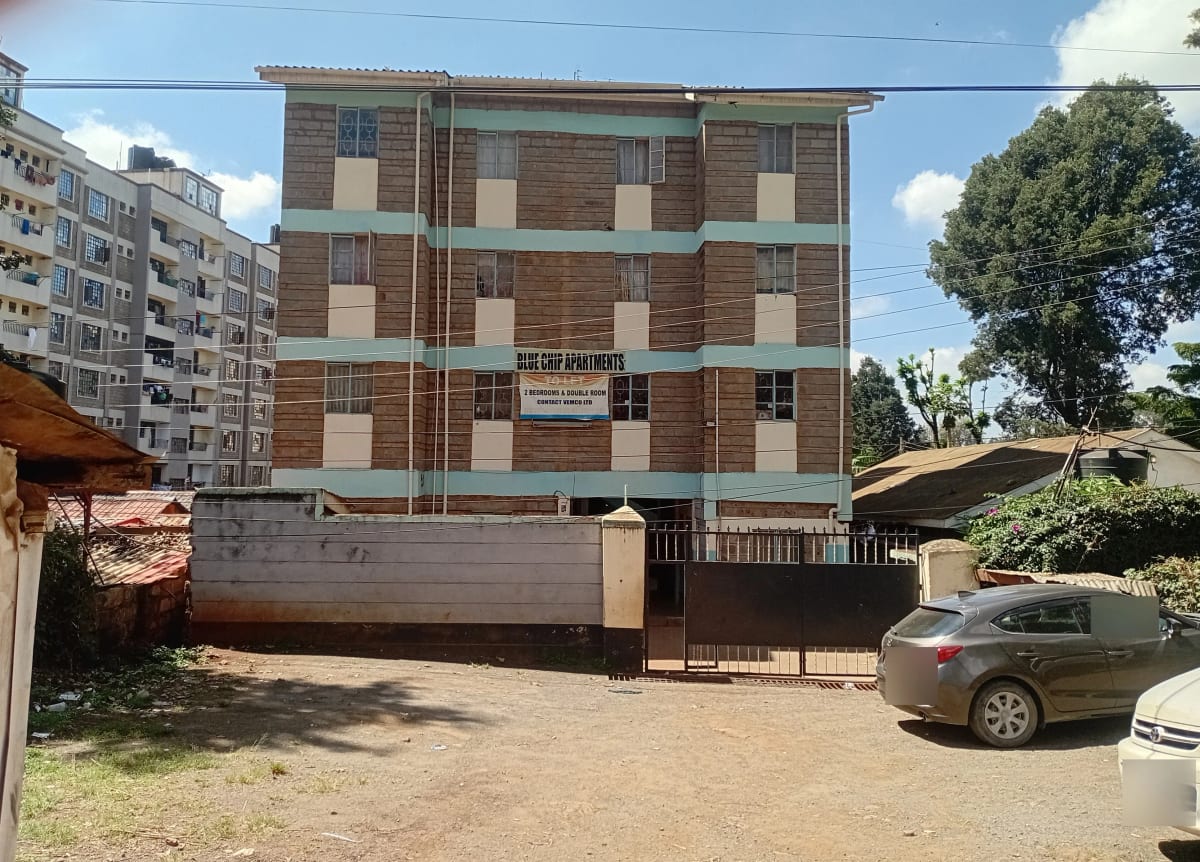 Four-story residential building with compound gate and parking area