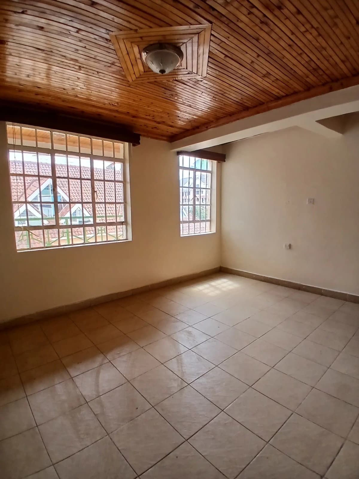 Spacious bedroom with wooden ceiling and barred windows