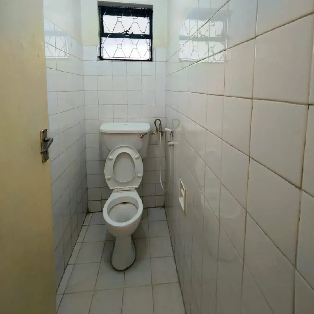 Compact toilet cubicle with white ceramic fixtures and tiled walls