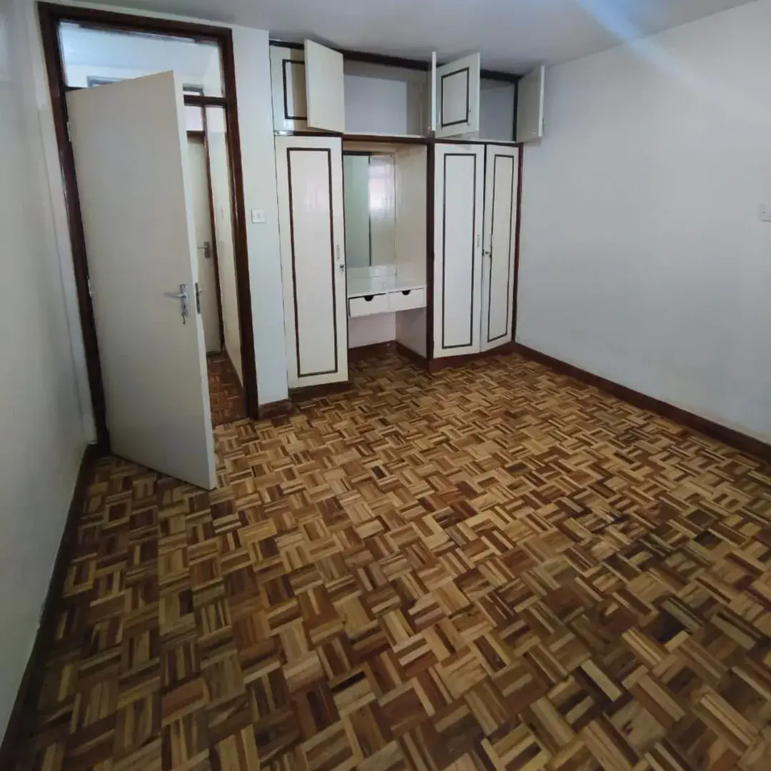Empty bedroom with herringbone parquet flooring and built-in wardrobes