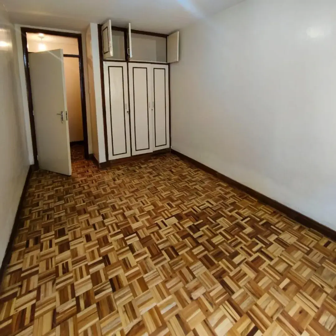 Spacious bedroom with parquet flooring and built-in wardrobes