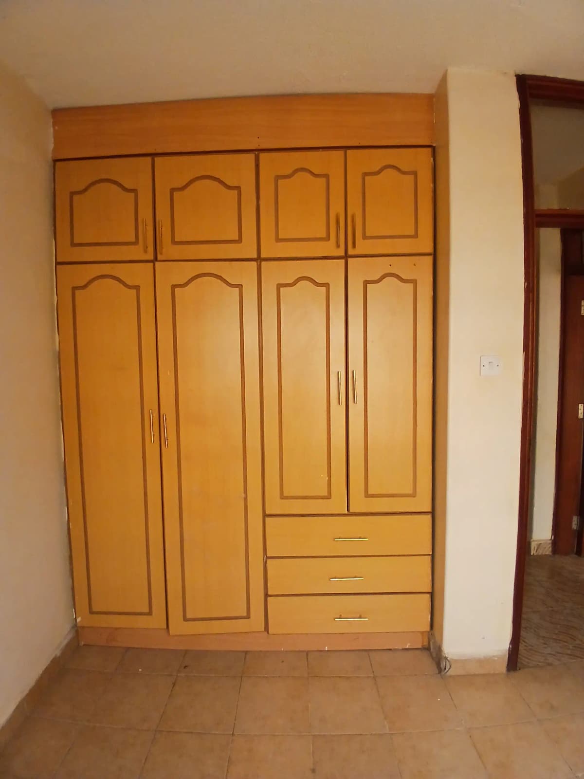 Bedroom with large wooden wardrobe and tiled flooring