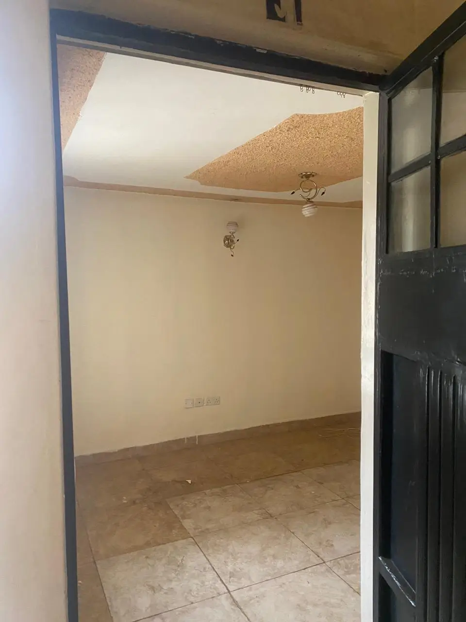 Empty bedroom with tiled floor and ceiling damage