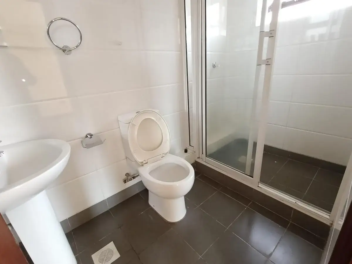 Clean bathroom with toilet, sink, and enclosed shower cubicle