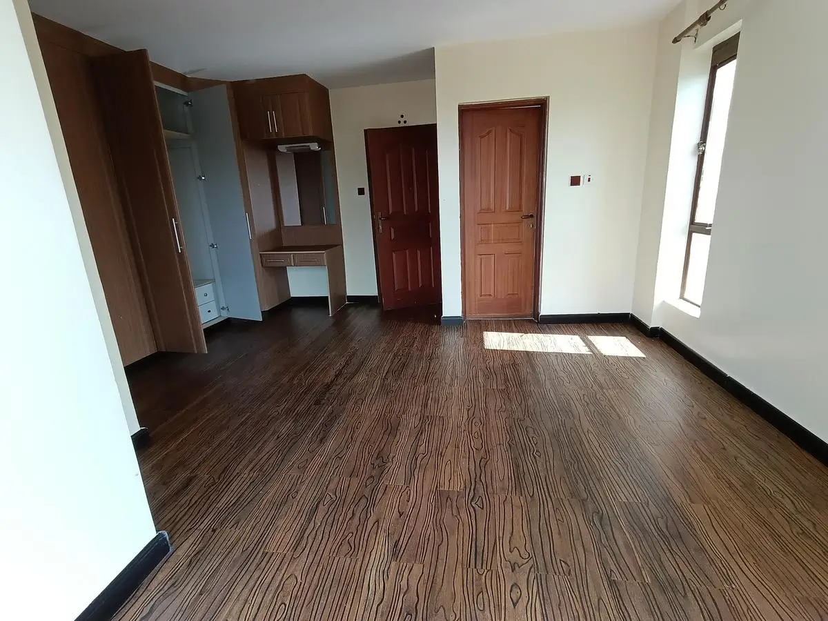 Spacious bedroom with wooden flooring and built-in wardrobes