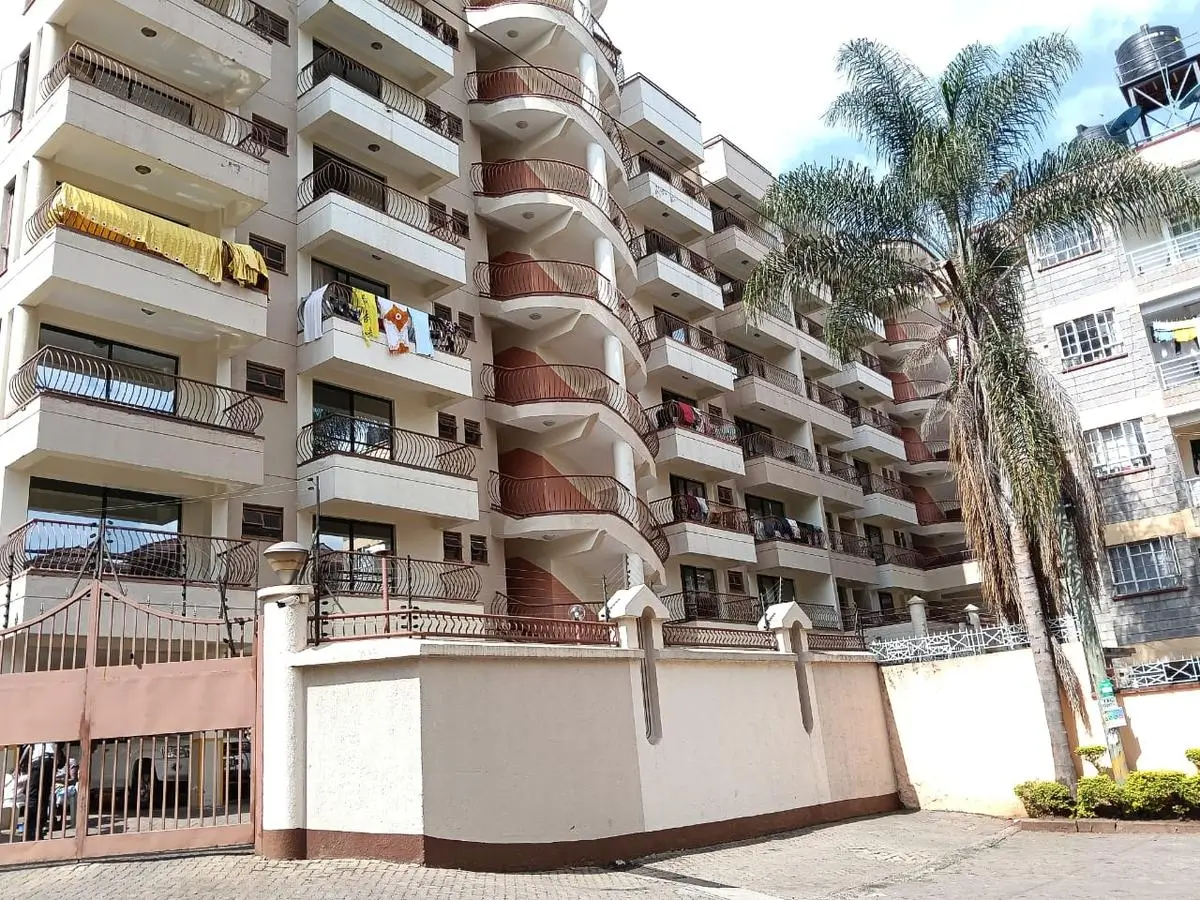 Multi-story residential building with curved balconies and compound gate