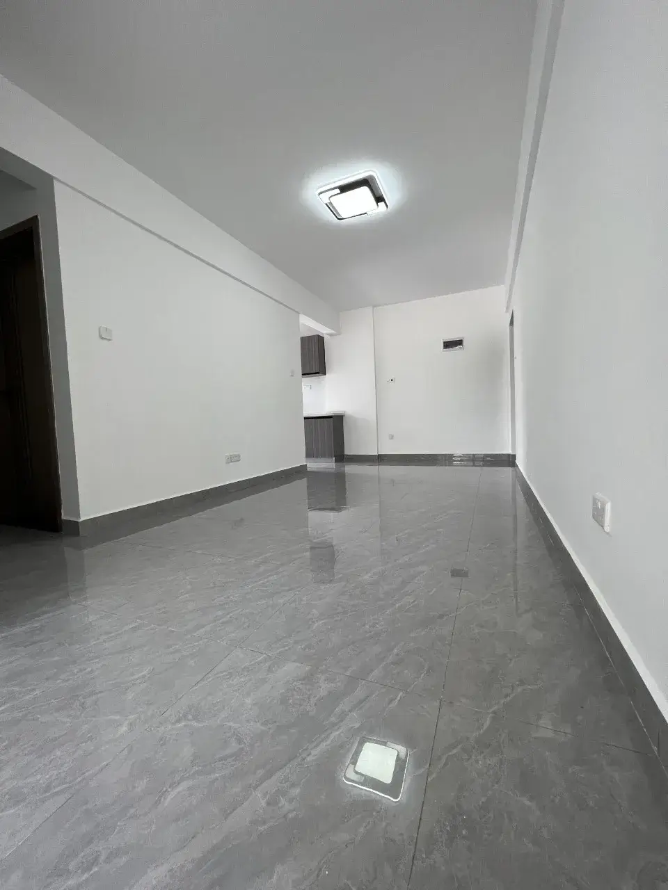 Empty corridor with gray tile flooring and white walls