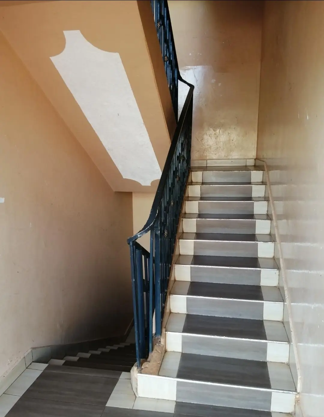 Interior staircase with black railing and striped steps