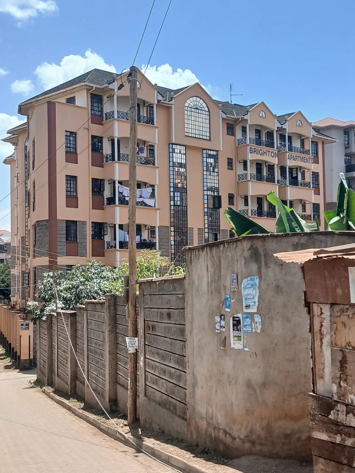 Multi-story residential building facade with surrounding compound wall