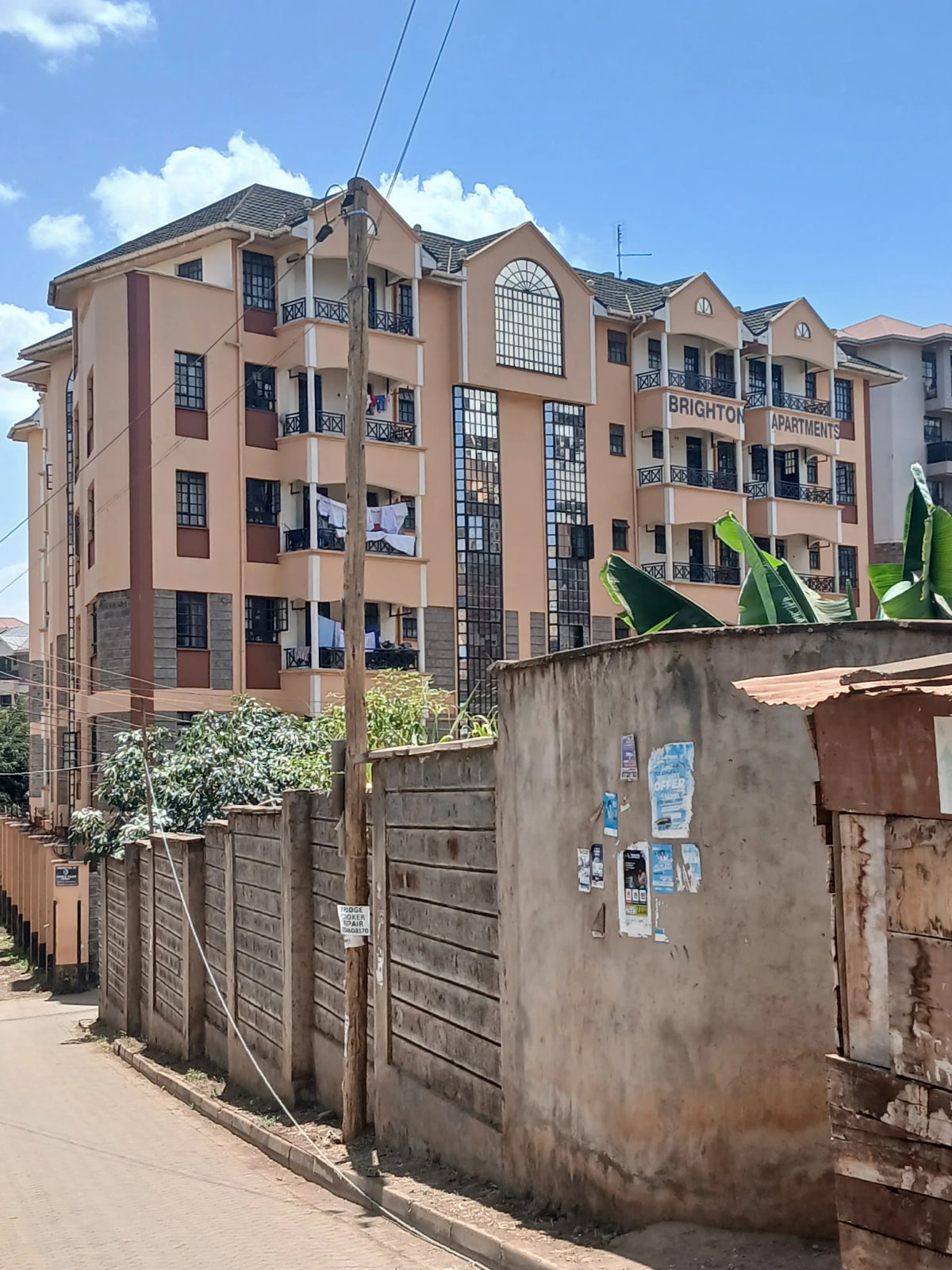 Multi-story residential building facade with surrounding compound wall