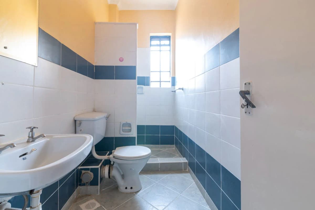 Compact bathroom with white sink, toilet, blue tile accents