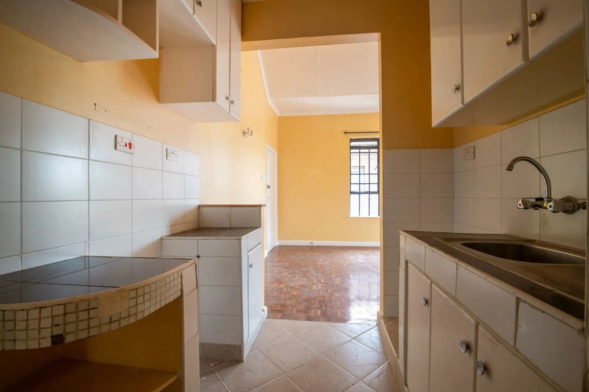 Galley kitchen with white cabinetry and separate pantry area