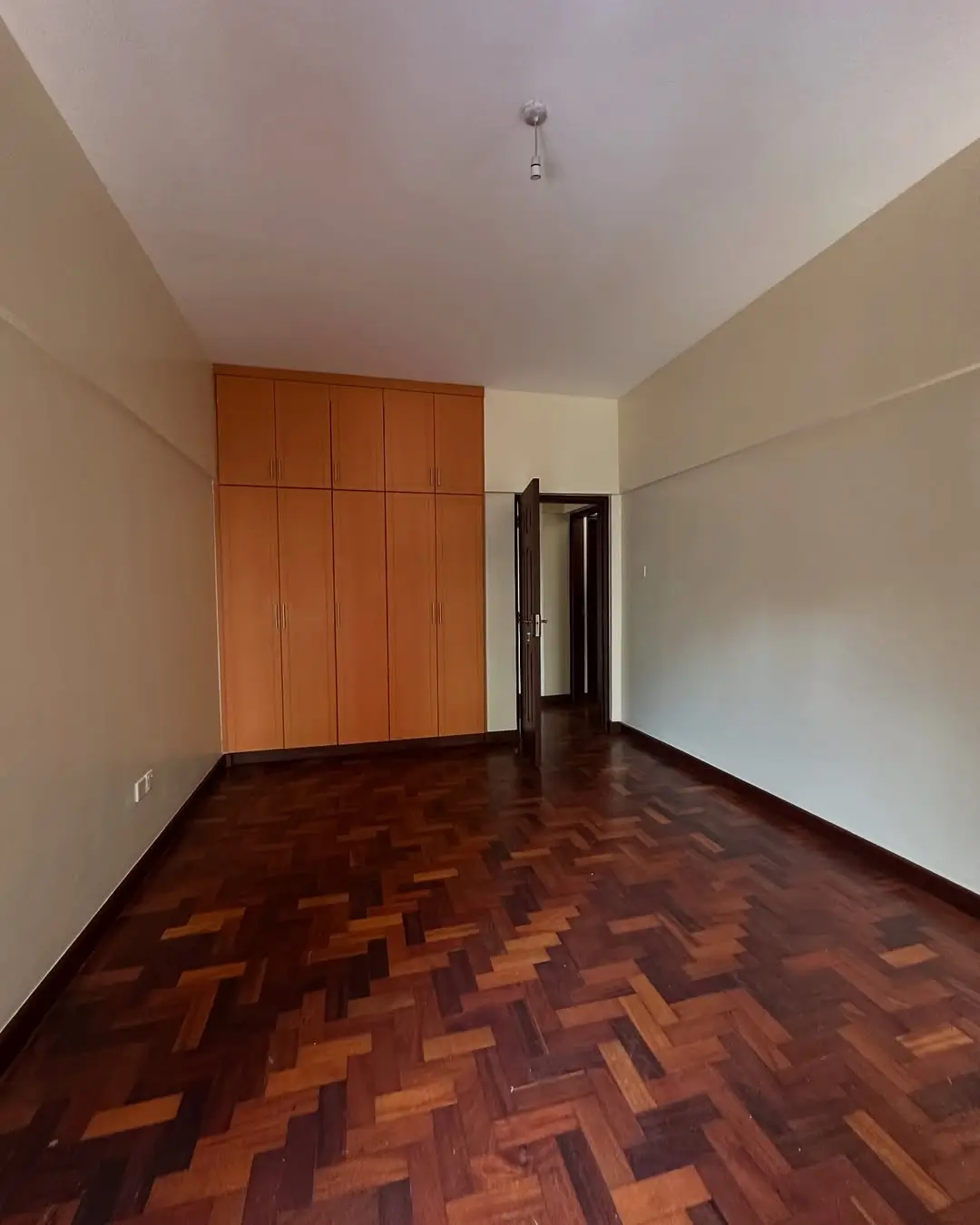 Spacious bedroom with wooden parquet floor and built-in wardrobe