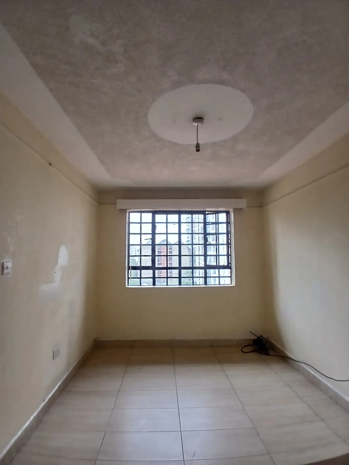Unfurnished bedroom with barred window and tiled floor