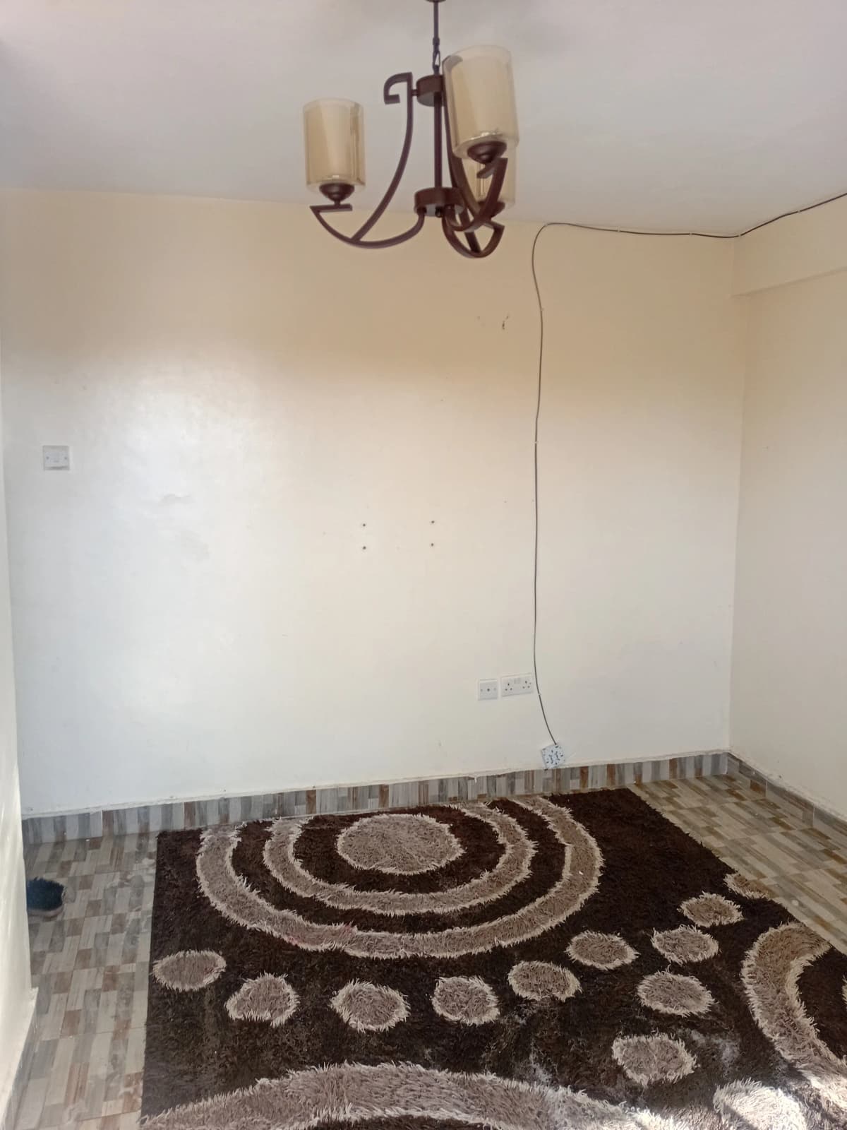 Unfurnished bedroom with pendant light and decorative rug