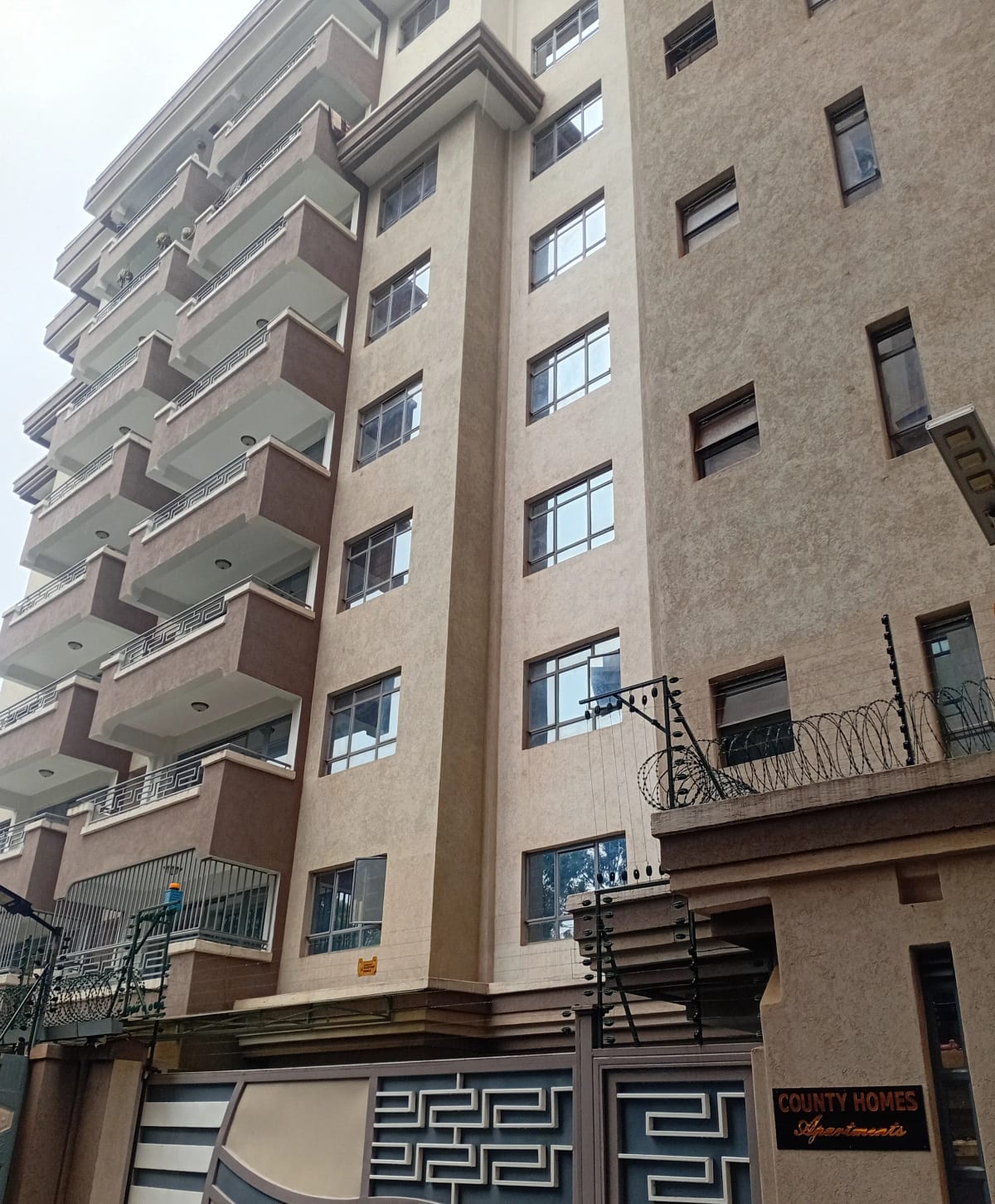 Multi-story residential building facade with balconies and entrance gate