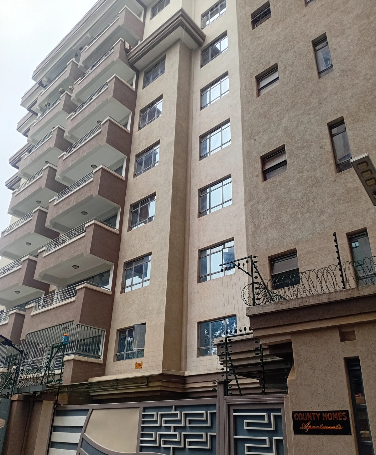 Multi-story residential building facade with balconies and entrance gate