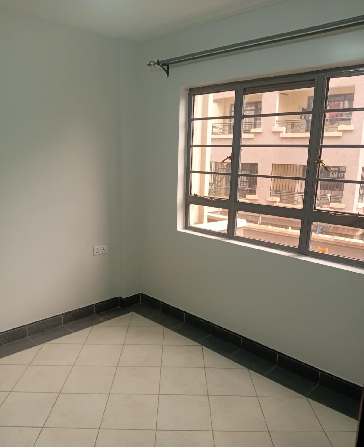 Empty bedroom with large window overlooking residential building