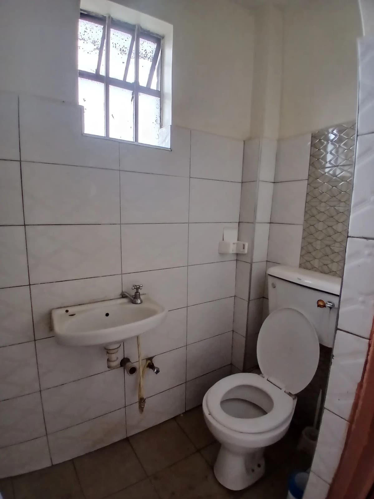 Basic bathroom with toilet, sink, and bright window
