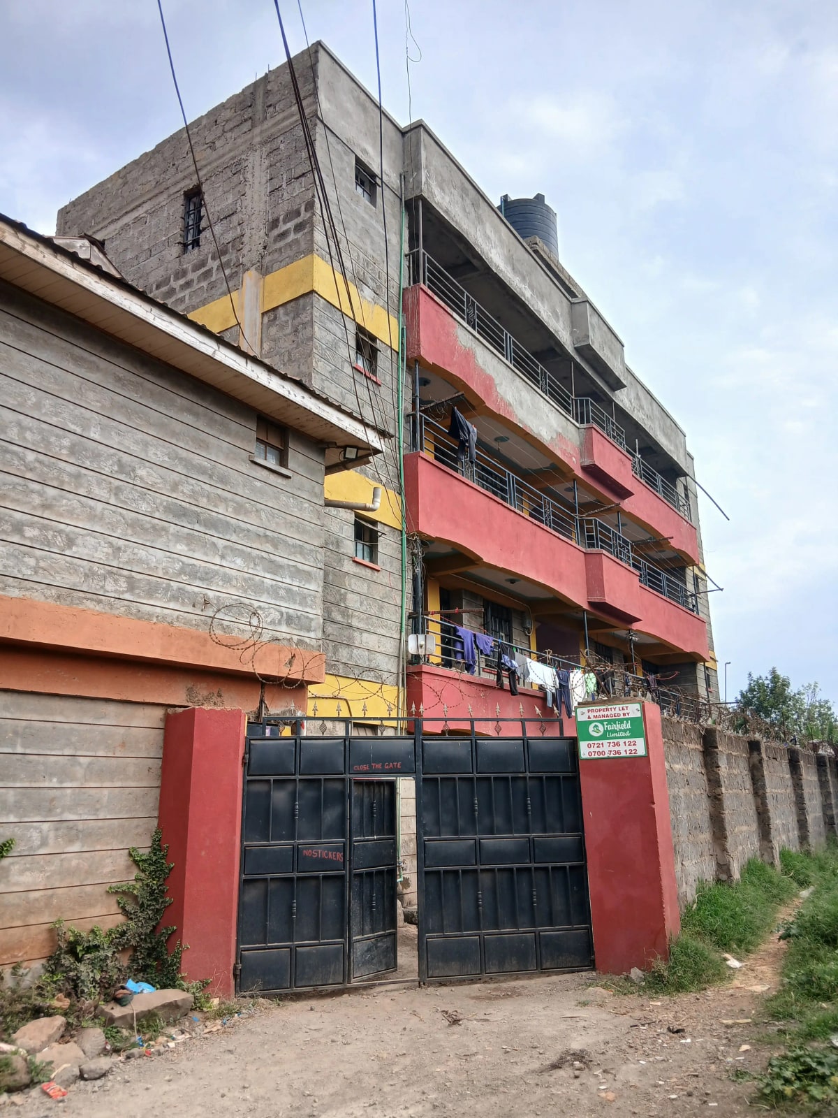 Multi-story residential building with red balconies and black gates