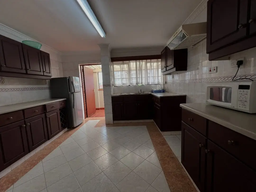 Spacious L-shaped kitchen with dark cabinets and tiled floor